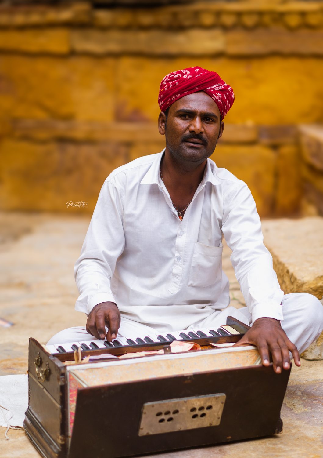 Folk musician in a red turban playing a harmonium