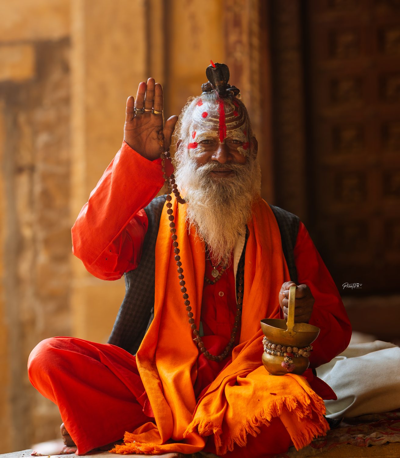 A sadhu in saffron raising his hand in blessing